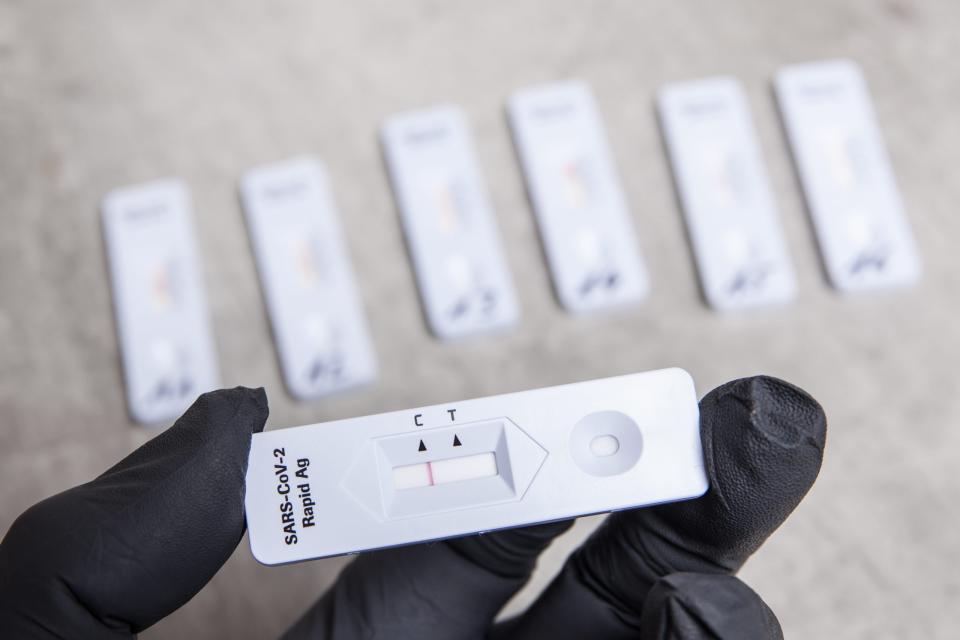 Eine Person mit Schutzhandschuhen hält eine Testkassette von einem negativen SARS-CoV-2 Rapid Antigen Test in der Hand