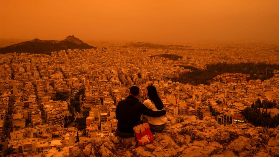 A couple sits on Tourkovounia hill, as southerly winds carry waves of Saharan dust, in Athens - 23 April 2024