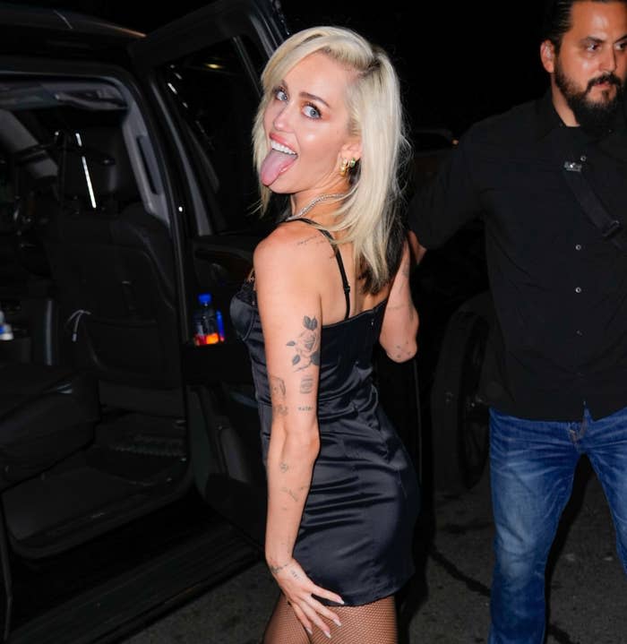 Miley sticks her tongue out at paparazzi as she walks toward a car