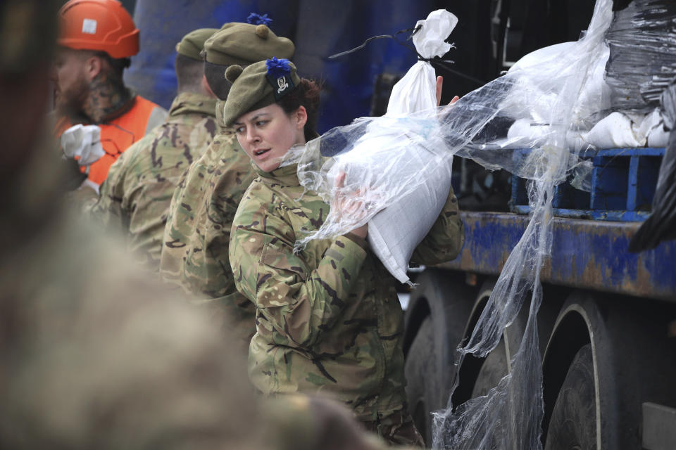 Soldados de The Highlanders, del 4to Batallón, del Real Regimiento de Escocia, descarga materiales para instalar defensas contra las inundaciones en momentos en que Gran Bretaña se prepara para enfrentar amplias secuelas de la tormenta Dennis en Mytholmroyd, West Yorkshire, en Inglaterra, el sábado 15 de febrero de 2020. (Danny Lawson/PA vía AP)