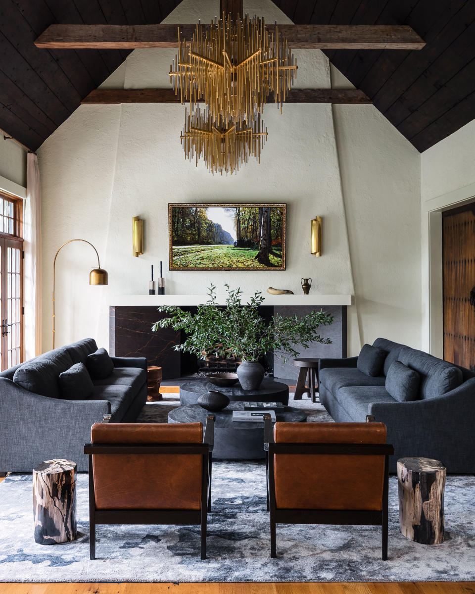 A large living room with a dark vaulted ceiling, two blue sofas facing one another, and a large fireplace