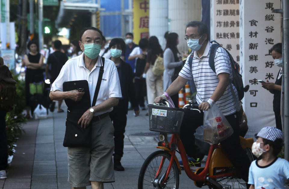 Pedestrians walk through the city streets wearing face masks to protect against the spread of the coronavirus in Taipei, Taiwan, Tuesday, July 28, 2020. (AP Photo/Chiang Ying-ying)