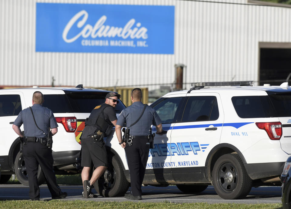 Police stand near where a man opened fire at a business, killing three people before the suspect and a state trooper were wounded in a shootout, according to authorities, in Smithsburg, Md., Thursday, June 9, 2022. The Washington County (Md.) Sheriff's Office said in a news release that three victims were found dead at Columbia Machine Inc. and a fourth victim was critically injured. (AP Photo/Steve Ruark)