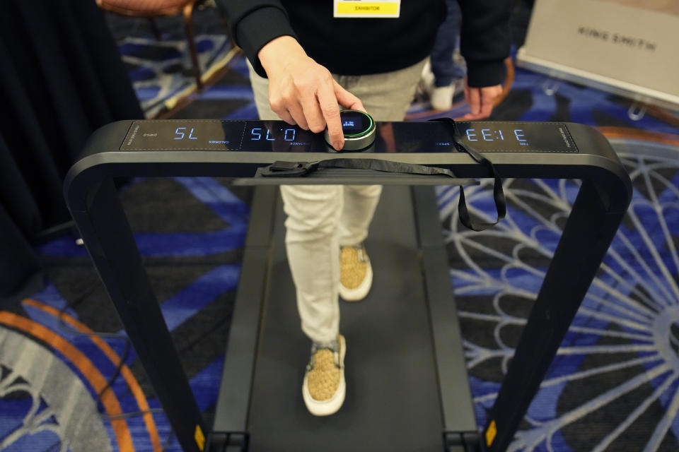 An exhibitor walks on the King Smith X21 WalkingPad Treadmill folding treadmill during the Pepcom Digital Experience before the start of the CES tech show, Wednesday, Jan. 4, 2023, in Las Vegas. (AP Photo/John Locher)