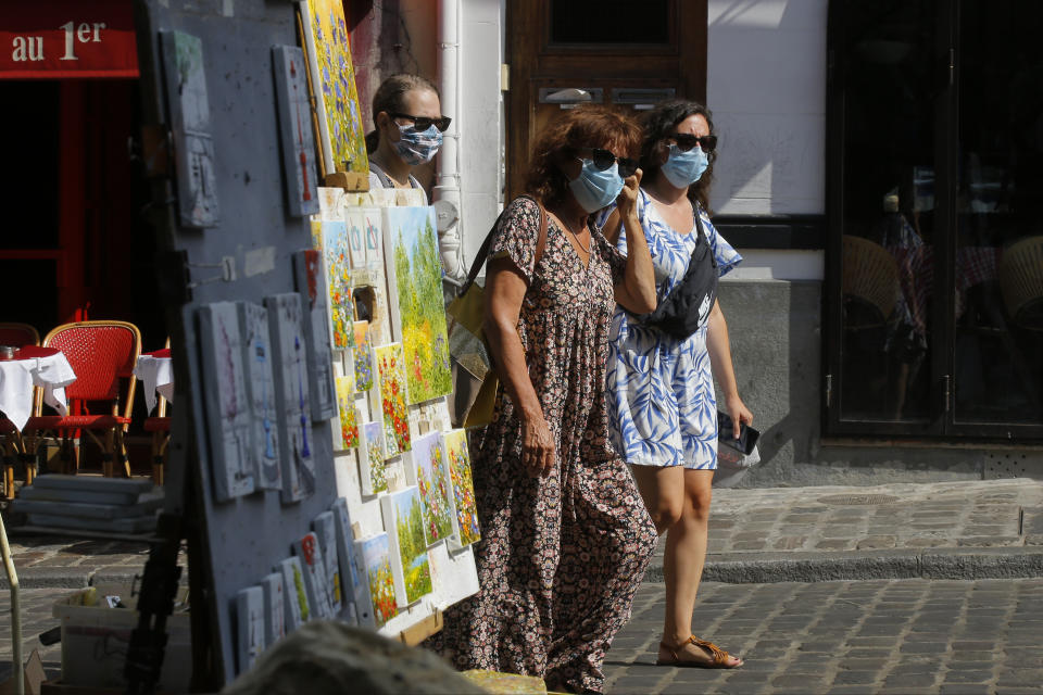 Tourists stroll in the Montmartre district Monday, Aug. 10, 2020 in Paris. People are required to wear a mask outdoors starting on Monday in the most frequented areas of the French capital. The move comes as the country sees an uptick in virus infections. (AP Photo/Michel Euler)