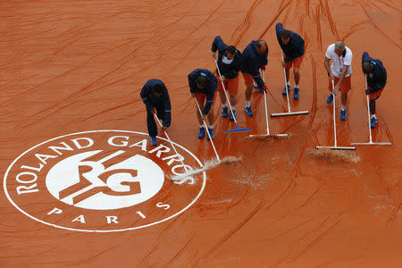 Court workers sweep away rain water during the French Open May 22, 2016. REUTERS/Pascal Rossignol