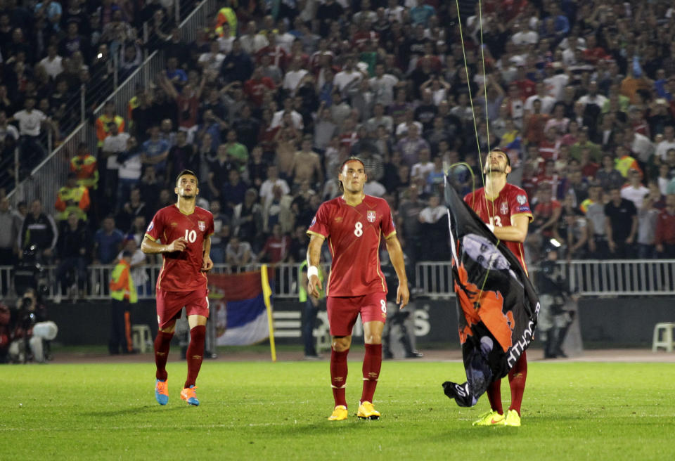 Serbia's Stefan Mitrovic grabs a drone which was flying a banner containing the Albanian flag during the Euro 2016 Group I qualifying match between Serbia and Albania in Belgrade, Serbia, Tuesday, Oct. 14, 2014. The match was suspended. (AP Photo/Darko Vojinovic)