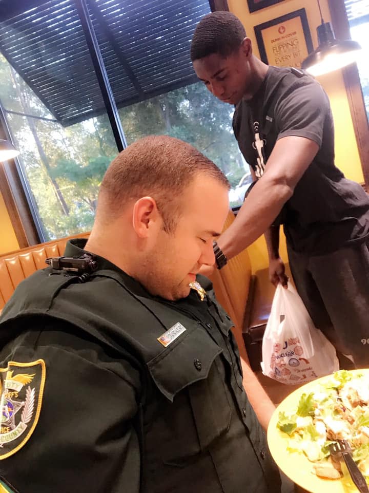 A Facebook photo of a Florida college student praying over a police officer has gone viral. (Photo: Facebook/Justine Tucker)