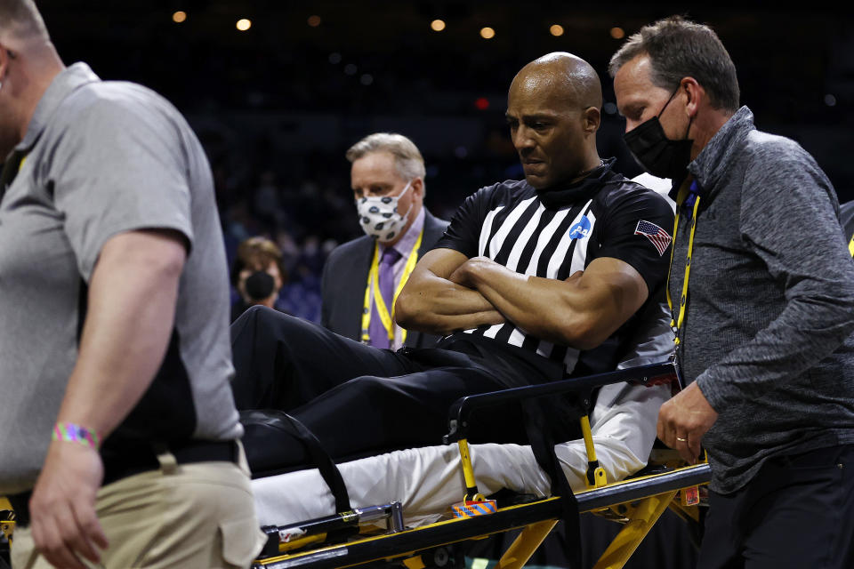 Referee Bert Smith is helped off the court by training staff and medical personnel after collapsing.