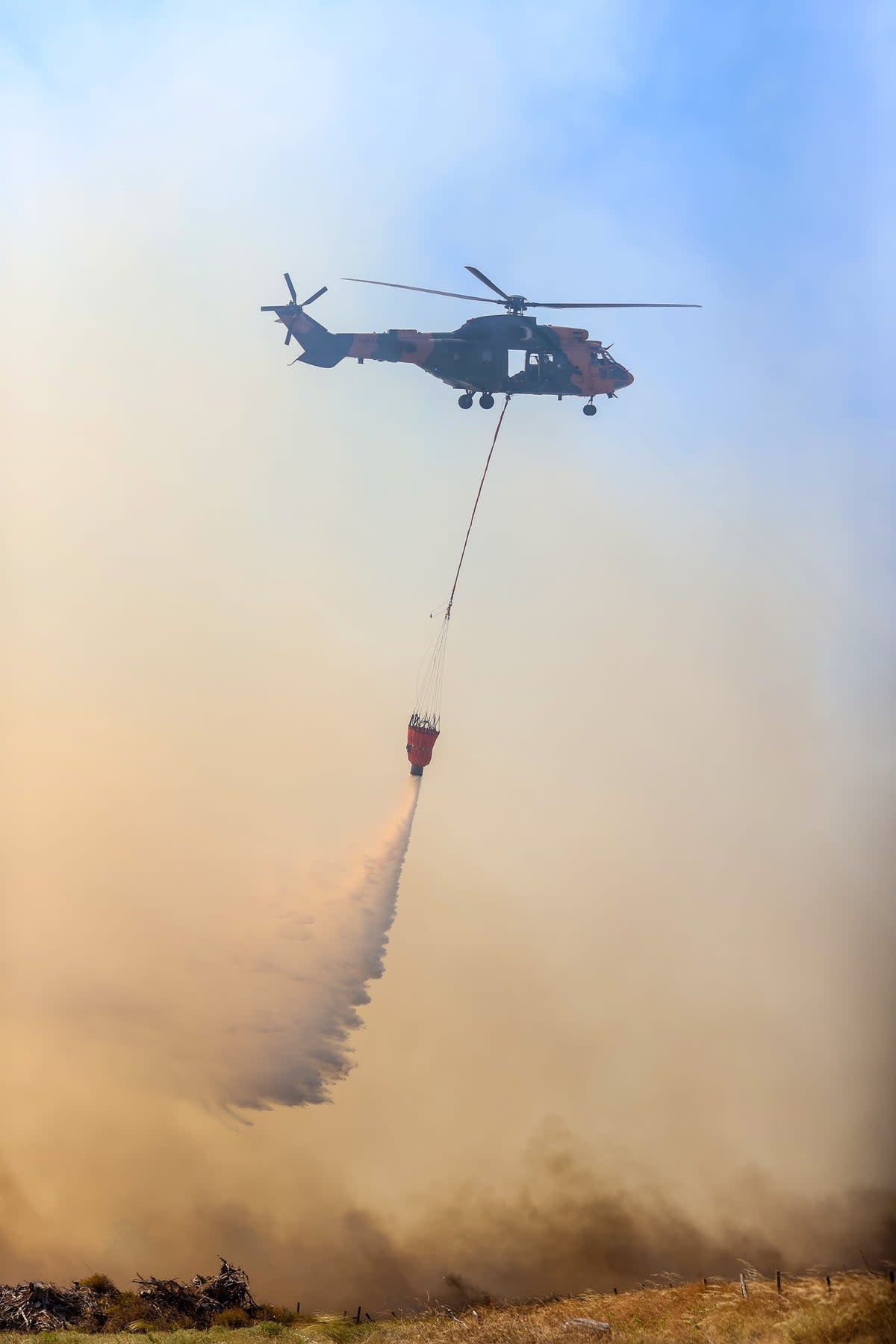 A firefighter helicopter drops water on wildfire as firefighter teams conduct extinguishing works by land and air to control wildfires in Canakkale, Turkiye on July 17, 2023 (Anadolu Agency via Getty Images)