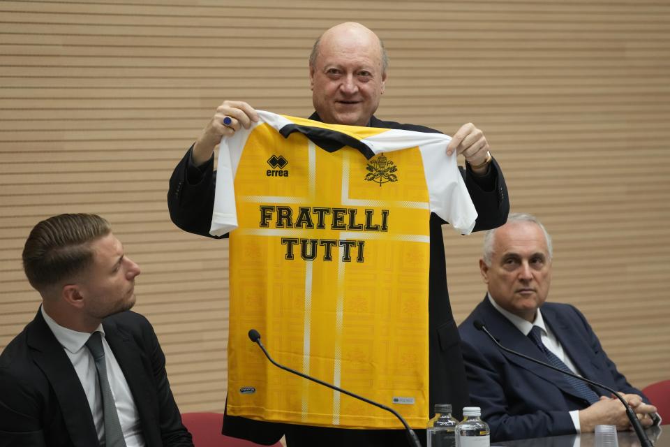 Cardinal Gianfranco Ravasi shows to journalists the jersey of the Vatican soccer team which will be donated to Pope Francis as he presents the soccer match between the Vatican soccer team "Fratelli Tutti" (All Brothers) and the World Rom Organization team, at the Vatican, Tuesday, Nov. 16, 2021. The match will be played Sunday, Nov. 21, at the Lazio training ground of Formello. (AP Photo/Gregorio Borgia)