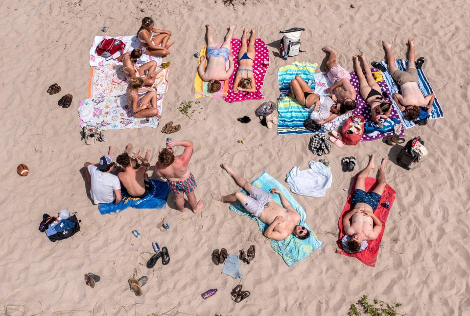 College students bask in the sun during spring break on Midtown Beach in Palm Beach, Florida on March 16, 2023.