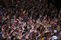 Anti-government protesters hold their hands up during the symbolic swearing-in of Juan Guaido, head of the opposition-run congress who declared himself interim president of Venezuela during a rally demanding President Nicolas Maduro's resignation in Caracas, Venezuela, Wednesday, Jan. 23, 2019. (AP Photo/Fernando Llano)