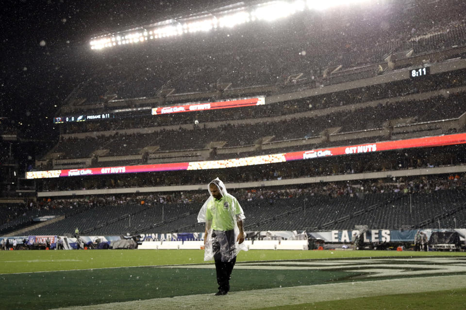 A worker walks the field during a rain storm as severe weather delays the start of an NFL football game between the Philadelphia Eagles and the Atlanta Falcons, Thursday, Sept. 6, 2018, in Philadelphia. (AP Photo/Michael Perez)