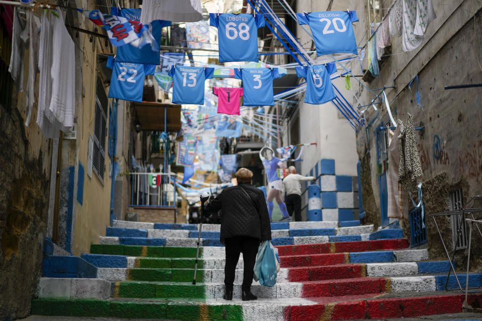 Una mujer camina entre pancartas del Napoli en el centro de Nápoles, Italia, el martes 18 de abril de 2023. El club está a punto de consagrarse campeón de la liga italiana por primera vez después de 30 años, desde la era de Diego Maradona. (AP Foto/Andrew Medichini)