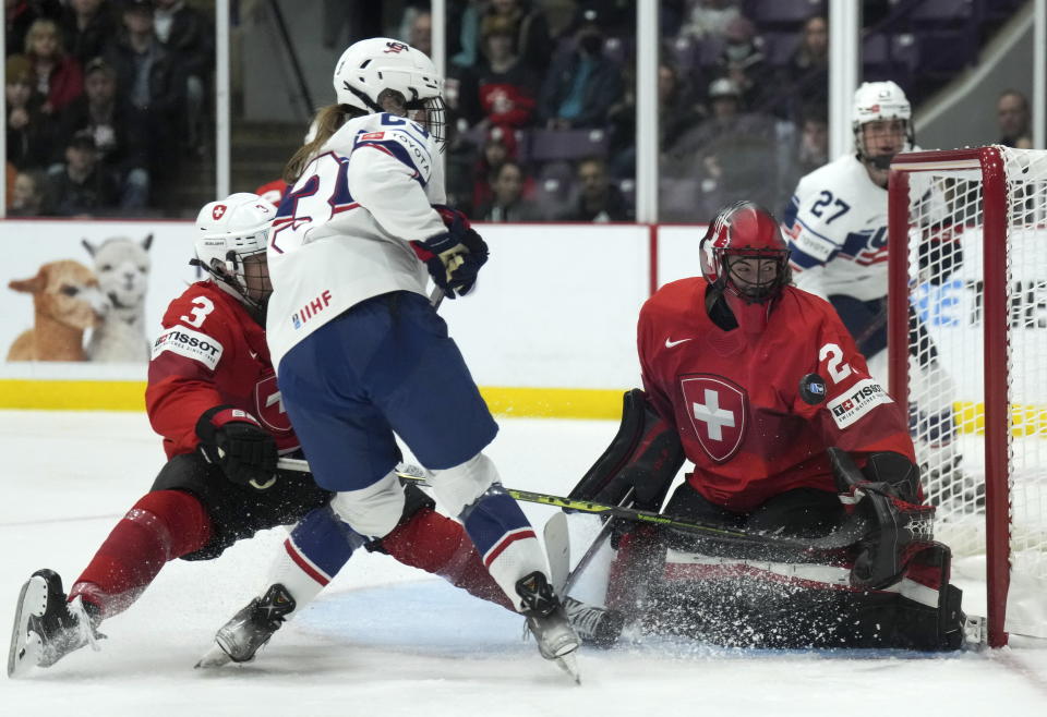 Switzerland goaltender Saskia Maurer (29) makes a save against United States forward Hannah Bilka (23) as Switzerland defender Sarah Forster (3) keeps close during the first period of a match at the Women's World Hockey Championships in Brampton, Ontario, Friday, April 7, 2023. (Nathan Denette/The Canadian Press via AP)