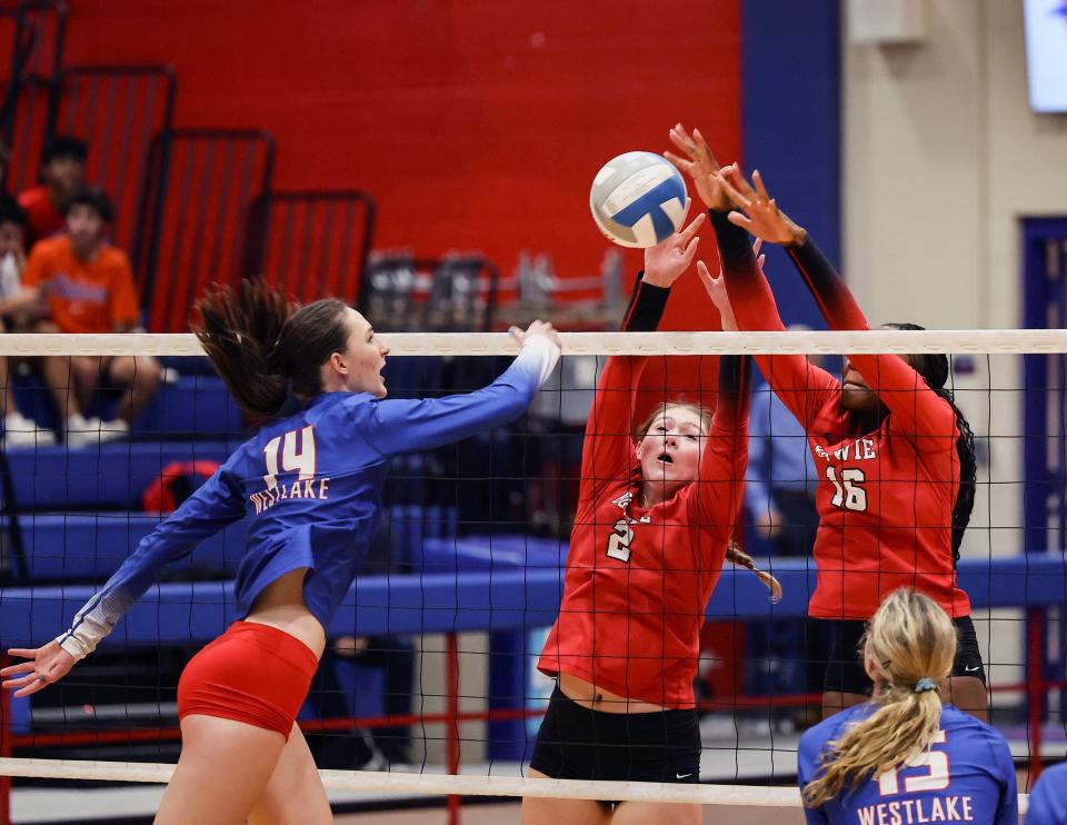 Allie Hudgins (14) hits through for Westlake as Bowie's Piper Justiss (2) and Simone Baskin (16) make the block in the district opener for both team August 22, 2023, at Westlake High School. 