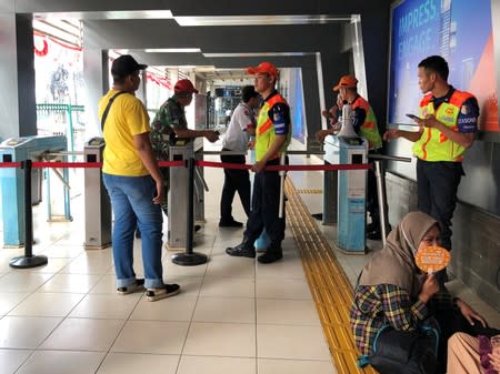 A man talks with a security officer at a Commuterline station as it is closed due to a major power blackout in Jakarta