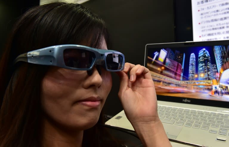 An employee of Japan's computer giant Fujitsu demonstrates a prototype of the 'Retissa' retinal imaging eyewear - which can project digital images onto the user's retina using laser beams, at CEATEC, in Chiba, suburban Tokyo, on October 7, 2015