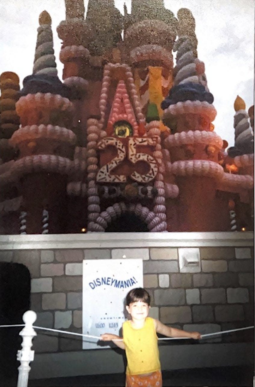 megan posing in front of the birthday cake cinderella castle at disney world for the 25th anniversary