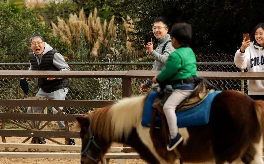 LOS ANGELES-CA - DECEMBER 6, 2022: Ethan Kim, 3, rides a pony as his grandfather Hwan, father Dennis, and mother Susan, from left, look on, during a family visit to Griffith Park Pony Rides on Tuesday, December 6, 2022. The city of Los Angeles will end its contract with Griffith Park Pony Rides due to threats of a lawsuit from an animal rights group. The group claims that the ponies were kept in inhumane conditions. Owner, Steve Weeks, is looking for new homes for its ponies. (Christina House / Los Angeles Times)