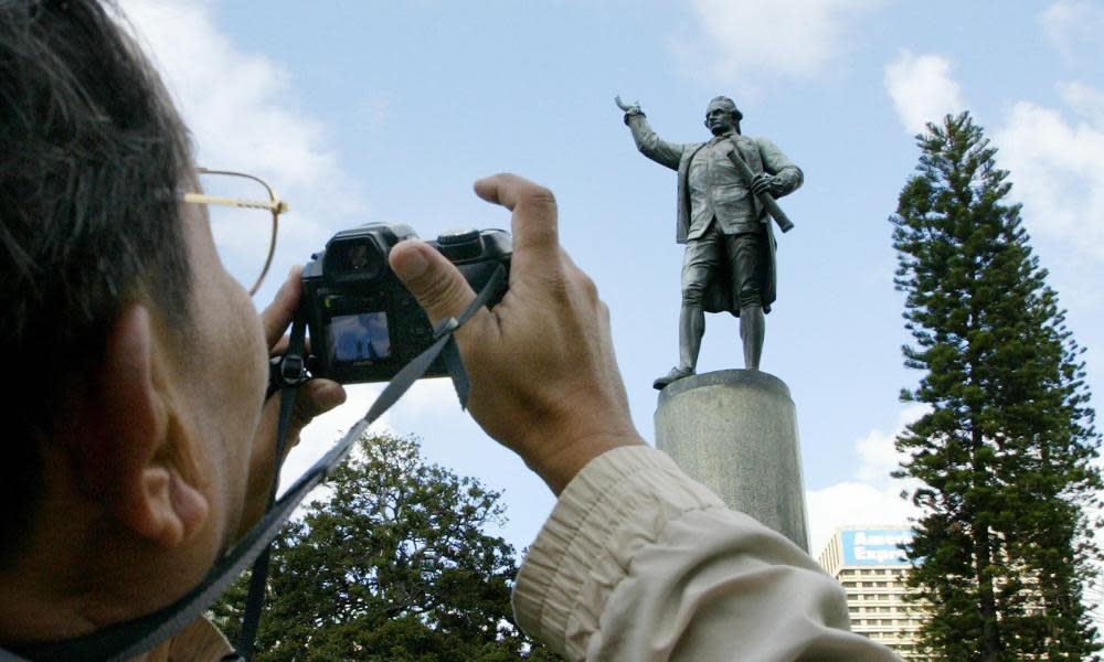 A tourist takes a photograph of the Captain Cook statue in Hyde Park, Sydney