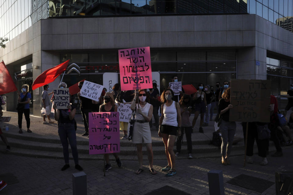 Israelis chant slogans during a demonstration against corruption near the house of Israel's Minister of Public Security In Tel Aviv, Israel, Thursday, July 30, 2020. Sign in Hebrew reads: "Ohana, fascism security minister" Referring to Amir Ohana Israel's Minister of Public Security. (AP Photo/Sebastian Scheiner)