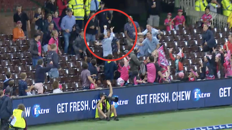 A crowd member jumps and takes a catch at the SCG.