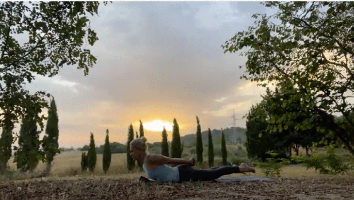 Woman practicing yoga at sunrise outside in a slight backbend on her mat