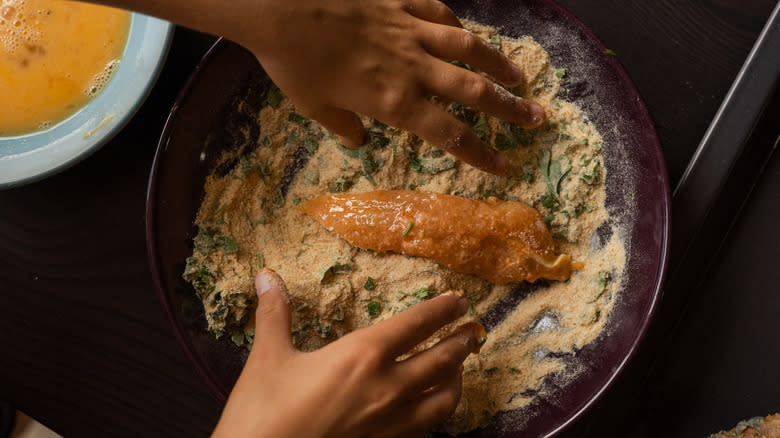 person coating fried chicken