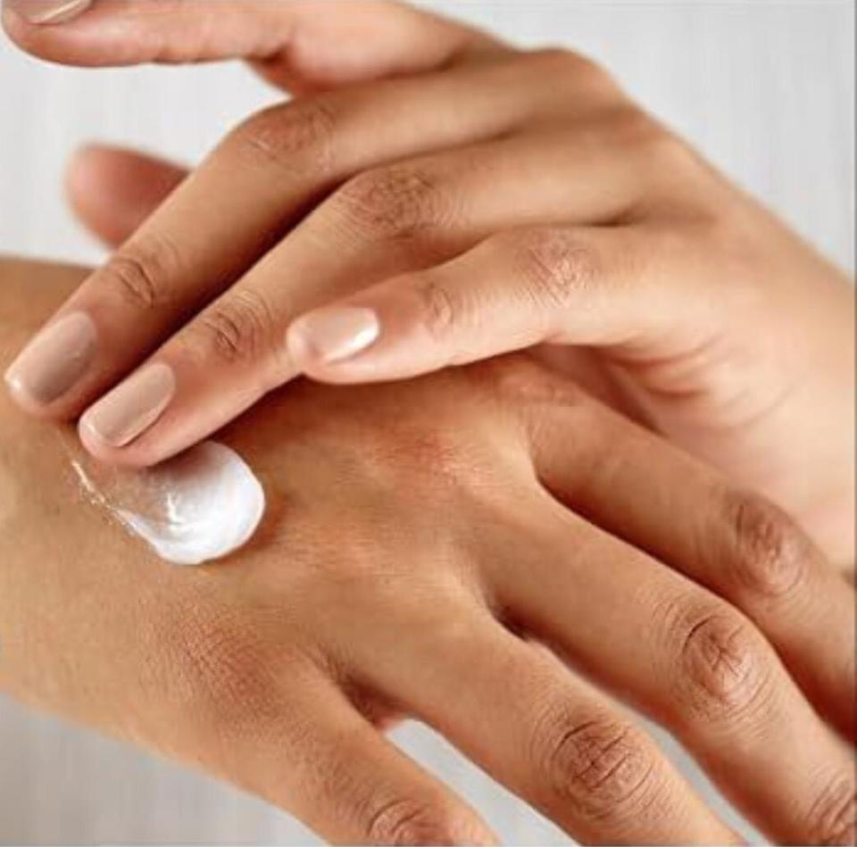 Person applying skincare cream on their hands