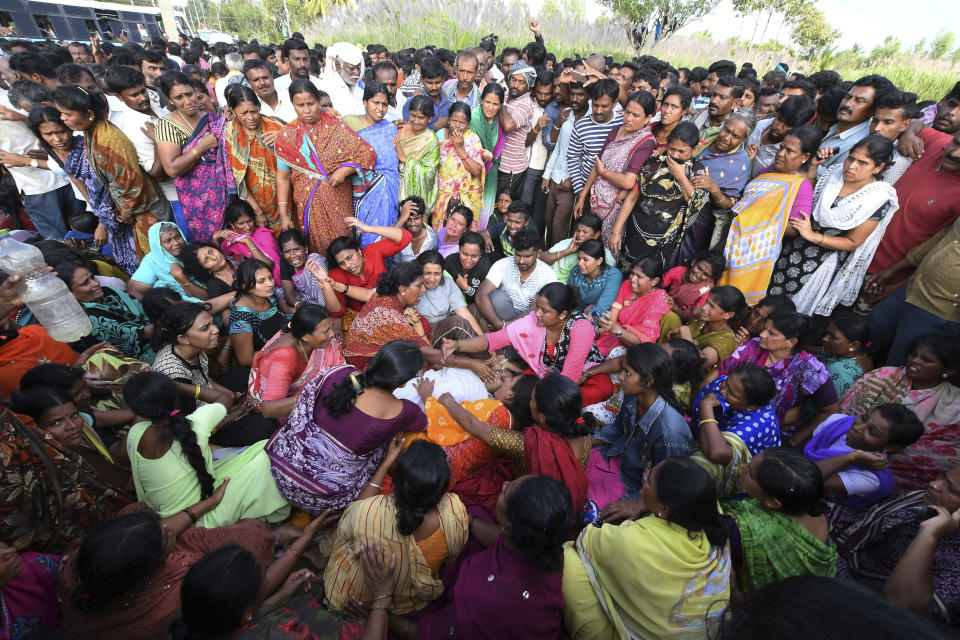 Relatives grieve as others gather around the body of a victim of a bus accident in Mandya district in the southern Indian state of Karnataka, Saturday, Nov. 24, 2018. At least 25 people, many of them schoolchildren, were killed when a speeding bus fell into a canal in southern India on Saturday, an official and media reports said. (AP Photo/Madhusudhan Sr)