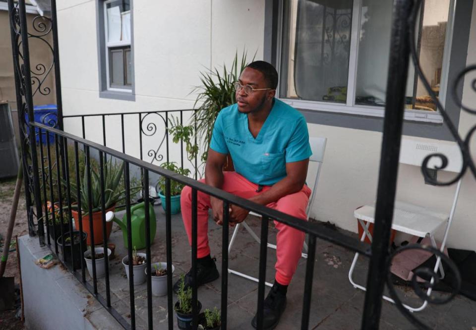 El Dr. Lawrence Rolle, en la foto en su porche de Miami tras un día de trabajo, es residente de segundo año en el Hospital Jackson Memorial. Con todos los postores al contado, para él fue todo un reto comprar finalmente una casa en Liberty City.