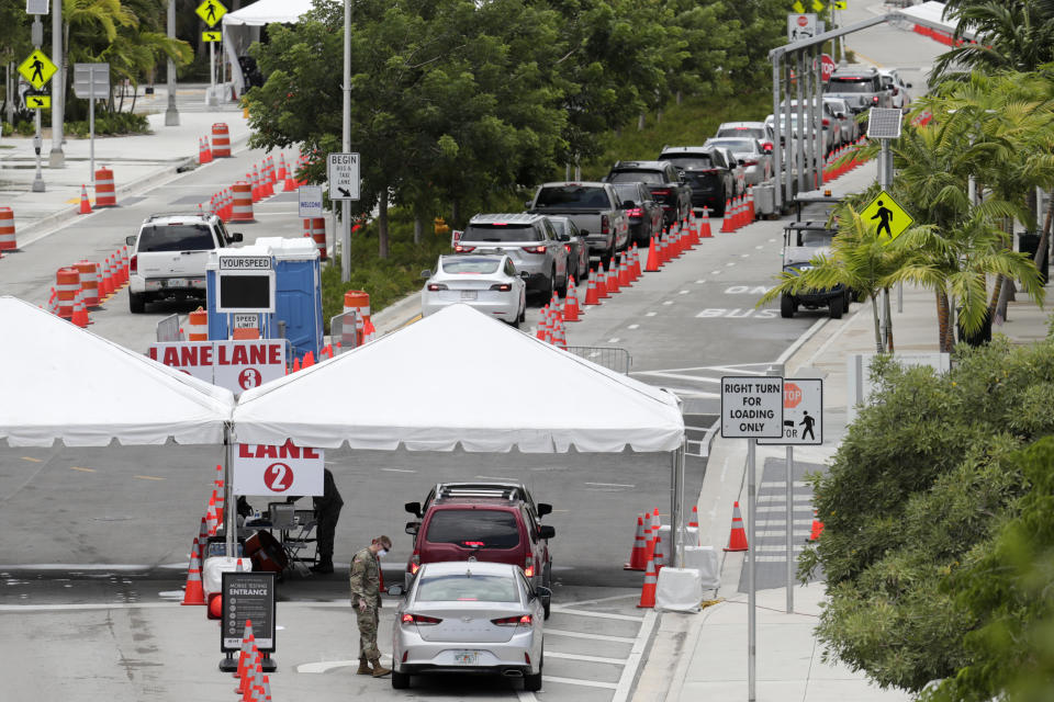 FILE - In this July 12, 2020, file photo, vehicles wait in line at a COVID-19 testing site at the Miami Beach Convention Center during the coronavirus pandemic in Miami Beach, Fla. The torrid coronavirus summer across the Sun Belt is easing after two disastrous months that brought more than 35,000 deaths. (AP Photo/Lynne Sladky, File)