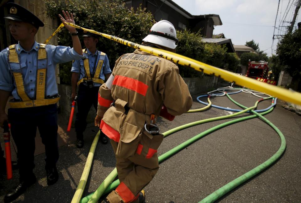 A firefighter rushes to the site where a light plane went down in a residential area and burst into flames, in Chofu, outskirt of Tokyo