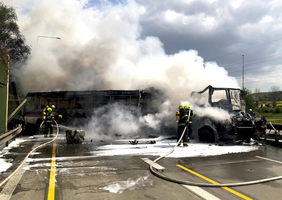 In this handout photo provided by Hasicsky Zachrany Sbor or HZS Praha, Czech Republic's firefighters put out remaining fire at the scene of a crash in Prague, Czech Republic, Thursday, May 2, 2019. Czech firefighters and police say a bus with prisoners caught fire after colliding with two trucks, one of them carrying two tanks. The Prague rescue service says one person has died in the crash that occurred on Thursday on a busy ring road that leads to Prague's international airport. (HZS Praha via AP)