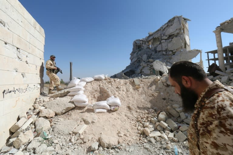 Rebel fighters walk on the rubble of destroyed buildings at a former research centre being used as a military barracks after they captured the complex, on July 4, 2015, on the western outskirts of Aleppo, Syria