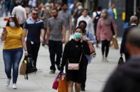 Shoppers walk along Oxford Street in London, Tuesday, July 14, 2020.Britain's government is demanding people wear face coverings in shops as it has sought to clarify its message after weeks of prevarication amid the COVID-19 pandemic. (AP Photo/Frank Augstein)