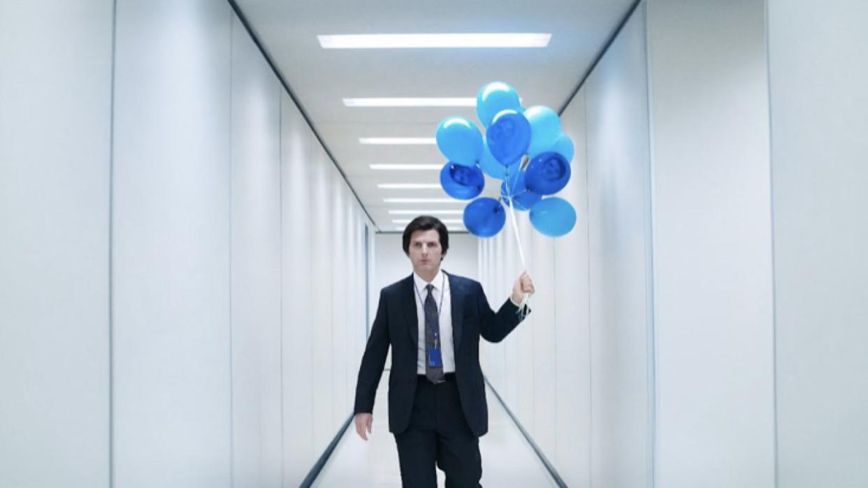  Adam Scott's Mark Scout is shown walking down a white hallway holding a bunch of blue balloons in an Apple TV+ image from Severance Season 2. 