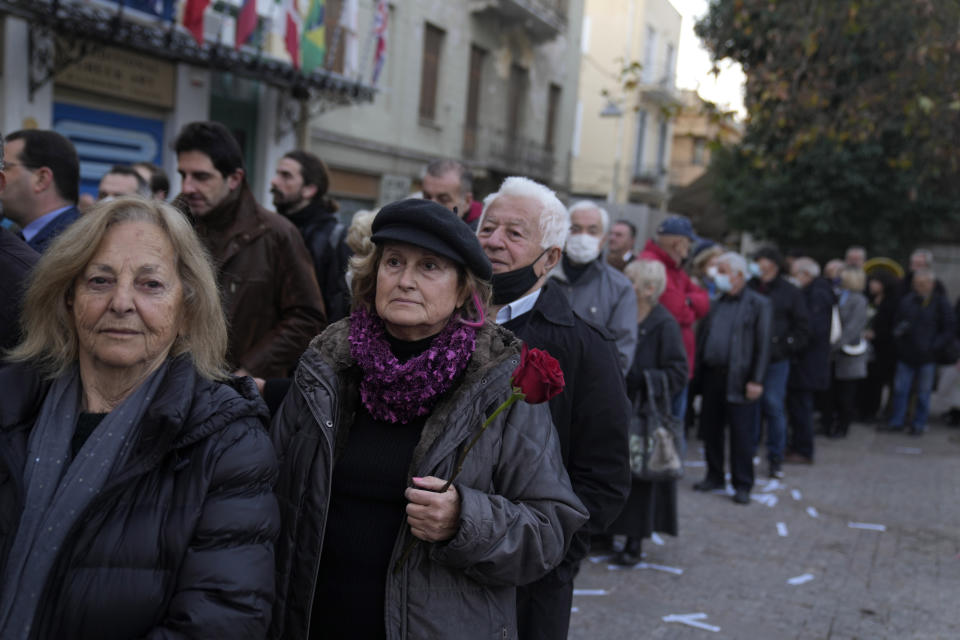 A woman holds a rose wait in the line with other people to enter in the Chapel of Saint Eleftherios as the coffin of the former king of Greece Constantine lies in repose in Athens, Monday, Jan. 16, 2023. Constantine died in a hospital late Tuesday at the age of 82 as Greece's monarchy was definitively abolished in a referendum in December 1974. (AP Photo/Petros Giannakouris)