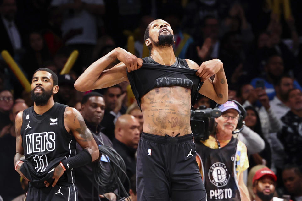 Brooklyn Nets forward Kevin Durant, front center, lifts up his jersey as Nets guard Kyrie Irving (11) untucks his own after the team defeated the Indiana Pacers in an NBA basketball game Monday, Oct. 31, 2022, in New York. (AP Photo/Jessie Alcheh)