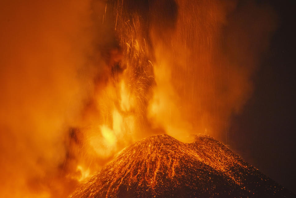 Lava and smoke are belched out from a crater as seen from the north-east side of the Mt Etna volcano near Milo, Sicily, Wednesday night, Feb. 24, 2021. Europe's most active volcano has been steadily erupting since last week, belching smoke, ash, and fountains of red-hot lava. (AP Photo/Salvatore Allegra)