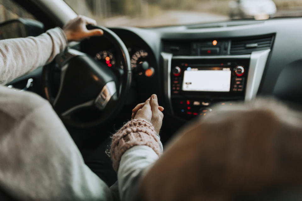 A couple in car holding hands