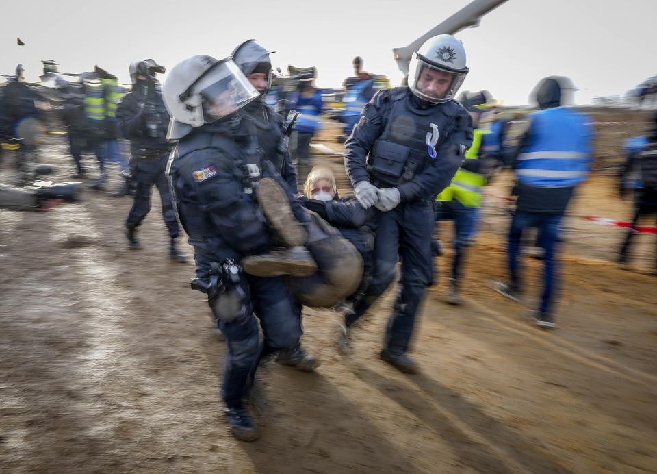 Police officers carry a demonstrator to clear a road at the village Luetzerath near Erkelenz, Germany, Tuesday, Jan. 10, 2023. The village of Luetzerath is occupied by climate activists fighting against the demolishing of the village to expand the Garzweiler lignite coal mine near the Dutch border. (AP Photo/Michael Probst)