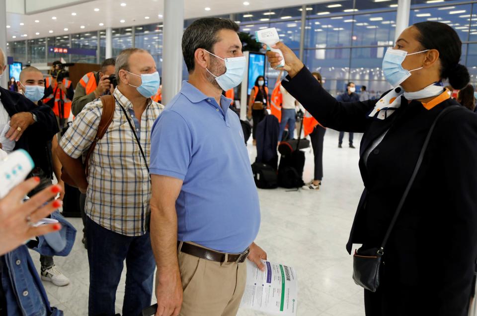 FILE PHOTO: A stewardess takes the body temperature of a man before boarding a plane at Paris-Orly Airport on its re-opening day following the coronavirus disease (COVID-19) outbreak in France, June 26, 2020. REUTERS/Charles Platiau