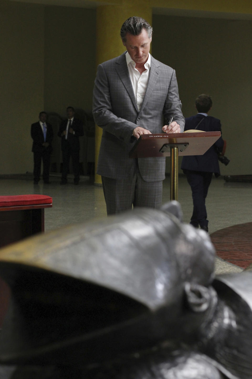 California Gov. Gavin Newsom writes a note on a book at the the tomb of Archbishop Oscar Romero at Metropolitan Cathedral in San Salvador, El Salvador, Sunday, April 7, 2019. Newsom visited the tomb of Archbishop Romero, the Salvadoran priest assassinated in 1980 due to his advocacy for human rights and the poor. (AP Photo/Salvador Melendez, Pool)