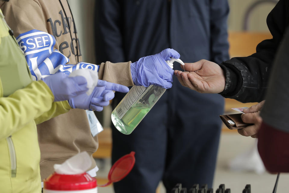 In this March 27, 2020 photo, a patient arriving to pick up medication for opioid addiction is given hand sanitizer at a clinic in Olympia, Wash., that is currently meeting patients outdoors and offering longer prescriptions in hopes of reducing the number of visits and the risk of infection due to the outbreak of the new coronavirus. The coronavirus pandemic is challenging the millions who struggle with drug and alcohol addiction and threatening America's progress against the opioid crisis, said Dr. Caleb Alexander of Johns Hopkins' school of public health. (AP Photo/Ted S. Warren)