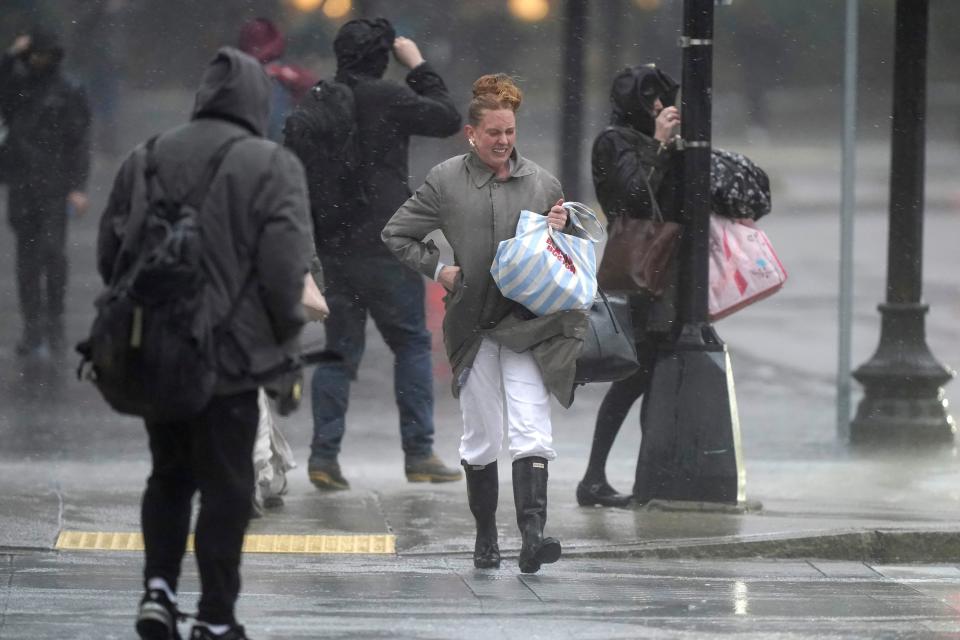 Pedestrians are buffeted by wind and rain as they cross a street, Monday, Dec. 18, 2023, in Boston. A storm moving up the East Coast brought heavy rain and high winds to the Northeast on Monday, threatening flooding, knocking out power to hundreds of thousands. (AP Photo/Steven Senne)