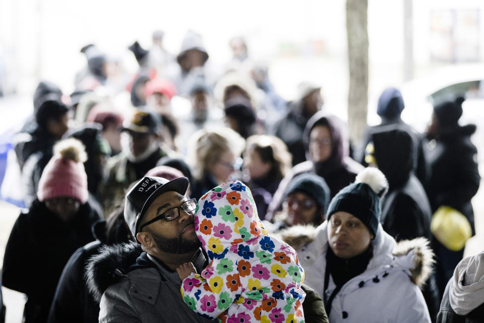 Anthony Spencer, whose wife, Chastity, right, is a furloughed federal worker, holds his daughter, Sydney, as they wait in line with others who are affected by the partial government shutdown for Philabundance volunteers to distribute food under Interstate 95 in Philadelphia, Wednesday, Jan. 23, 2019. (AP Photo/Matt Rourke)