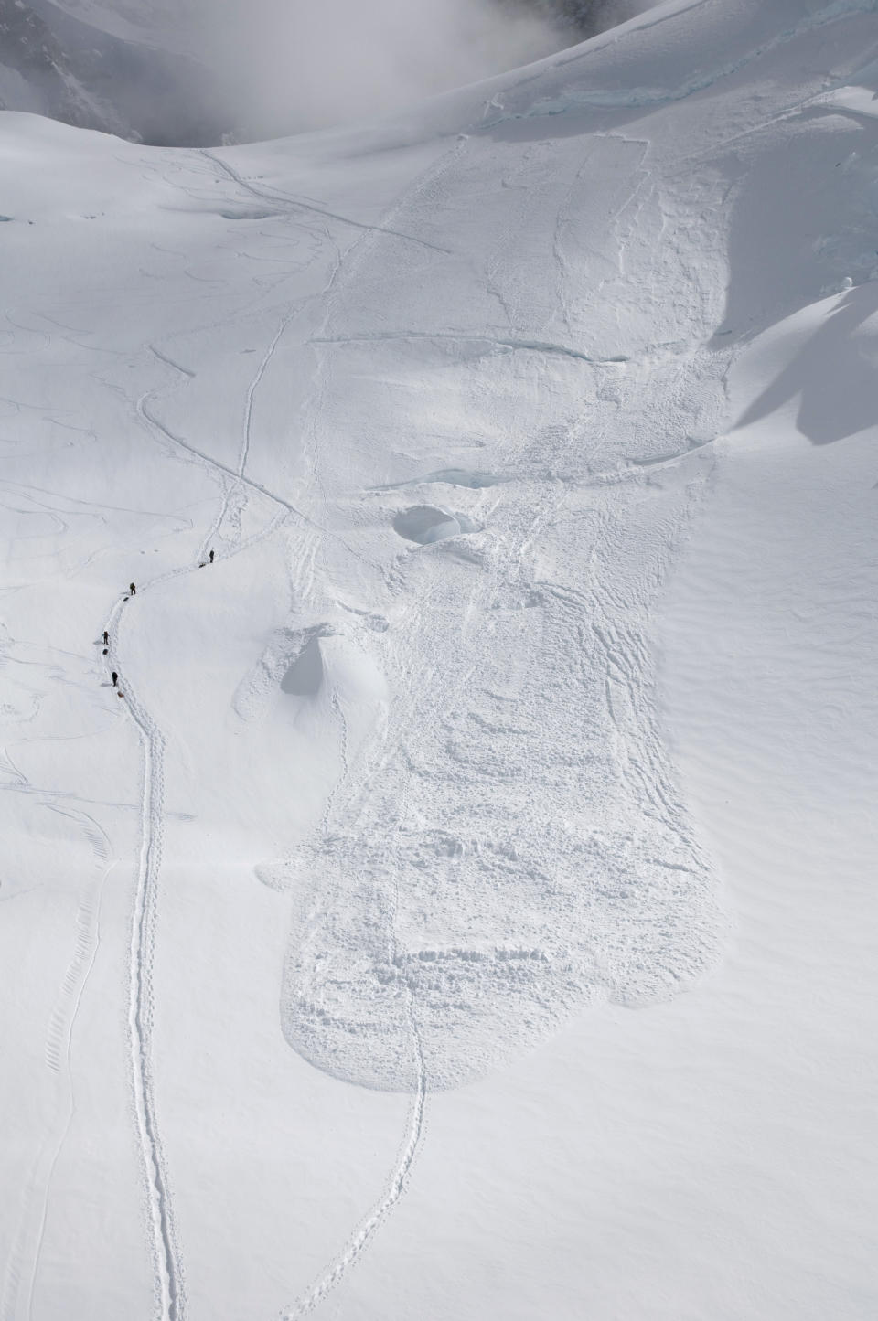 In this Friday, June 15, 2012 photo provided by the National Park Service, climbers hike through the area where an avalanche swept a Japanese climbing team off a hill during their descent from Alaska's Mount McKinley. U.S. National Park Service officials say five people were traveling as a one rope team early Thursday morning as part of a Miyagi Workers Alpine Federation expedition on the Alaska mountain. The NPS said Hitoshi Ogi, 69, survived after falling 60 feet (18 meters) into a crevasse. He was able to climb out. The other four tumbled into the avalanche debris and haven't been seen since. (AP Photo/National Park Service, Kevin Wright)